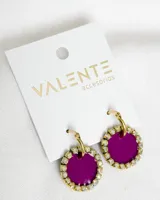 Aros colgantes con forma circular, de color violeta con borde de strass dorados y gancho dorado.