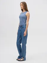 Pantalón de denim color marrón, de tiro alto y calce ochentoso con terminación estilo oxford. Cuenta con apliques metálicos decorativos alrededor de los bolsillos y a lo largo de las costuras exteriores.
