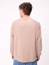 Sweater de cuello redondo y manga larga con diseño de hombros raglán, confeccionado en tejido de punto acanalado con efecto lavado. Presenta un pequeño logo bordado en el pecho.