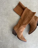 Bota de caña media color marrón chocolate, de gamuza, con punta fina y taco cónico.