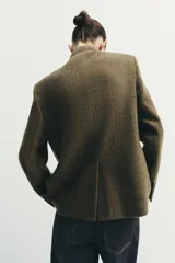 Blazer estructurado de corte recto confeccionado en tejido con lana, con estampado de cuadros en tonos tierra. Presenta cuello subido, cierre frontal con un botón, bolsillos con solapa en la parte inferior y un bolsillo de vivo en el pecho.
