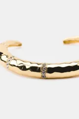 Gargantilla rígida de metal dorado con acabado labrado y textura irregular, decorada con bandas de cristales brillantes incrustados.