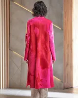 Tapado largo de lana merino afieltrada, color fucsia con diseño tie-dye artesanal en tonos claros y crudos. Tiene cuello que se prolonga a modo de cinto, aberturas laterales y bolsillos.