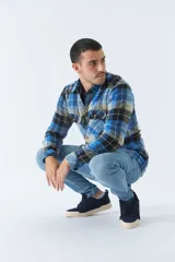 Sobrecamisa de algodón a cuadros color ladrillo, con interior de corderito, cierre con botones, bolsillos tipo cartera y logo en goma. El modelo usa talle M.