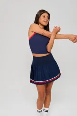 Conjunto deportivo compuesto por un top sin mangas de cuello redondo con detalles en contraste y una pollera tableada de tiro alto con franjas decorativas en el ruedo.