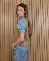 Chaleco marrón de denim con pespuntes en contraste, cuello redondo y cierre frontal con botones.