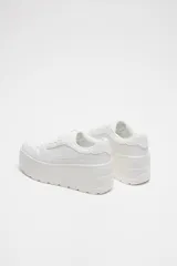 Zapatillas blancas tipo bamba con plataforma de 7 cm, cierre con cordones y punta redonda.