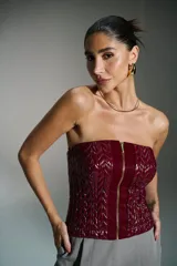 Corset rojo con cierre frontal con cremallera dorada y diseño geométrico en relieve.