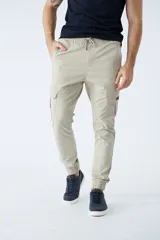 Pantalón cargo color beige con ajuste slim, cintura elastizada con cordón ajustable, bolsillos laterales con solapa y puños elásticos en los tobillos.