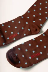 Medias largas color marrón con estampado de lunares celestes. Tienen un corazón rojo bordado con la letra 'R' en blanco en la parte superior y la palabra 'Rotunda' en rojo en el lateral del pie.