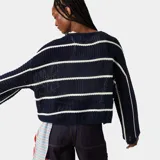 Sweater de punto grueso, color azul marino, con rayas horizontales blancas y cuello redondo. Presenta un tejido calado en la parte superior y un texto bordado en blanco en la manga derecha que dice "EMESTUDIOS".