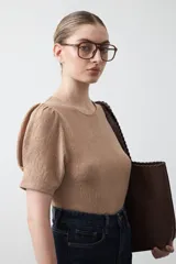 Remera negra de manga corta con textura floral en relieve. Presenta un diseño de inspiración romántica con mangas ligeramente abullonadas que aportan estructura y un ajuste al cuerpo.