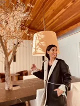 Gamulán negro con interior de corderito blanco, cuello alto, cierre frontal con broches y bolsillos laterales. Presenta tajos a los costados para mayor movilidad.