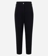 Pantalón zanahoria negro de tiro alto confeccionado en crepé de poliéster con elastano. La prenda tiene hebillas en los laterales, pliegues, cierre tradicional de botón y cremallera, además de bolsillos.