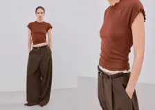 Camiseta color marrón, de manga corta, con cuello redondo y terminaciones con ondas tipo lechuga en el cuello, mangas y dobladillo.