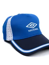 Gorro tipo visera Umbro del Club Nacional de Football, en colores azul marino y rojo con detalles blancos en la visera. Cuenta con el logo de la marca y la inscripción "Nacional" bordados en el frente.