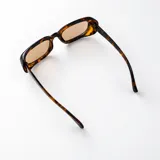 Lentes de sol con armazón rectangular de policarbonato marrón translúcido y cristales degradados en tonos rosados.