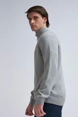 Buzo de punto gris claro melange con cuello alto y medio cierre.