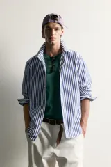 Camisa relaxed fit confeccionada en tejido de algodón, con diseño de rayas verticales en tonos azul y blanco, cuello con botones y manga larga.