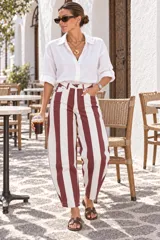 Pantalón de denim con diseño de rayas verticales en colores bordo y blanco, de tiro alto y corte amplio con silueta tipo balloon, bolsillos funcionales y presillas para cinturón.