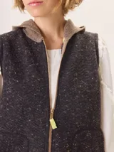 Chaleco de punto con capucha, confeccionado en lana. Presenta un diseño bicolor con cuerpo en tono beige de textura acanalada y capucha en tono marrón. Incluye una etiqueta de cuero en la parte posterior.