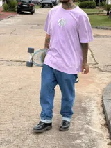 Remera color beige de algodón premium, manga corta y cuello redondo. Presenta un estampado circular en el centro del pecho con un diseño abstracto en tonos grises.