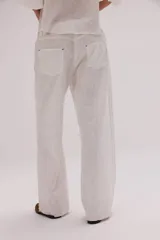 Pantalón de lino lavado color beige, de calce recto y diseño relajado. Presenta cintas de lino desflecadas aplicadas en los laterales con pespunte central, pretina con botón metálico, bolsillos delanteros y traseros.