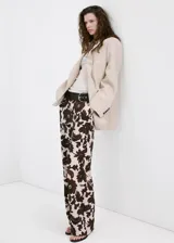 Pantalón largo de corte recto y tejido fluido, con diseño estampado floral en tonos marrón y crudo, bolsillos laterales y cierre oculto.