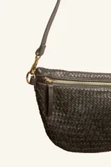 Bandolera color marrón, de cuero trenzado a mano, con forma semicircular, cierre superior y correa regulable.