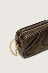 Bolso tipo camera bag de cuero vacuno marrón con acabado envejecido y craquelado, diseño de estrella en relieve en el frente, herrajes dorados y correa de cadena.