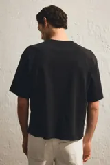 Remera negra de punto de algodón pesado, corte boxy holgado, con cuello redondo ribeteado acanalado, hombros caídos y bajo recto.