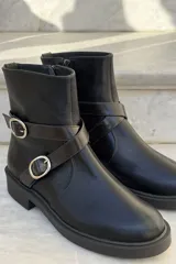 Bota corta de cuero charolado color bordó, con suela track negra, cierre lateral y tiras decorativas con hebillas metálicas plateadas.