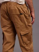 Pantalon tipo jogger cargo color marron, con cintura elastizada con cordon de ajuste, bolsillos laterales con solapa y puños elastizados en los tobillos.