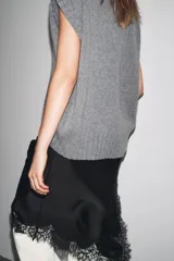 Chaleco oversize de lana color gris, con cuello redondo, manga sisa y bajo asimétrico con aberturas laterales.