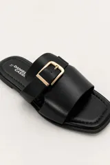 Sandalias planas color borravino con tiras cruzadas y hebilla dorada decorativa en el empeine.