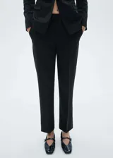 Pantalon de vestir negro de corte slim fit, con tiro medio, detalle de pinzas frontales, bolsillos laterales y cierre oculto con botón, gancho y cremallera.