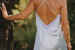 Camisón de satén elastizado color celeste, con escote en V con detalle de puntilla blanca y breteles finos cruzados en la espalda.