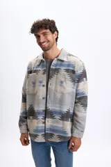 Sobrecamisa de corte recto con diseño estampado de motivos tribales en tonos gris, azul y marrón. Presenta cuello clásico, cierre frontal con botones y dos bolsillos frontales con solapa.