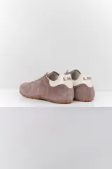 Zapatillas deportivas marrones de gamuza con cordones blancos y detalles en cuero blanco en el talón.