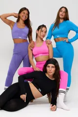 Conjunto deportivo de tres piezas en color negro, compuesto por un top de manga larga con cuello redondo y logo estampado, un top de bretel ancho y una calza chupín de tiro alto. El diseño presenta detalles de tejido con textura en zonas estratégicas.