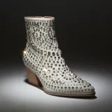 Bota texana de caña media en color blanco, completamente cubierta de tachas metálicas plateadas. Presenta un taco cuadrado de madera y punta ligeramente afinada.