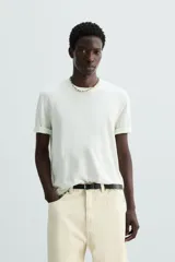 Camiseta relaxed fit de punto ligero color blanco hueso, con cuello redondo y manga corta. Acabados en rib.