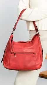 Cartera de hombro color negro, confeccionada en material símil cuero con textura granulada. Presenta un diseño estructurado con cierre superior, bolsillo frontal con cierre horizontal, bolsillos laterales con cierre y herrajes metálicos. Incluye una correa de hombro fija y una correa larga regulable extraíble.