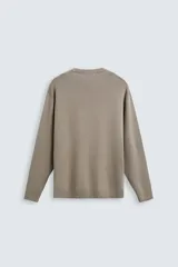 Jersey color crudo de tejido de punto, con cuello redondo y mangas largas. Corte amplio y terminaciones en rib.