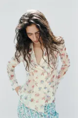 Camisa de cuello solapa y manga larga, con estampado de flores y cierre frontal cruzado.