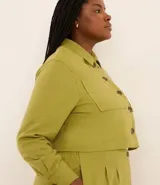 Campera corta color verde oliva, confeccionada en viscolino, con cuello inglés, abotonada adelante, bolsillos y manga larga ajustada.