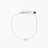 Pulsera de cadena fina plateada con un dije central de cristal en forma ovalada. Incluye cierre de mosquetón y cadena de alargue con pequeño dije circular grabado.