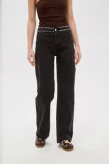 Pantalon de jean negro de corte recto y tiro alto, con detalle de tachas metálicas en la cintura.