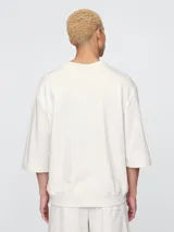 Remera de corte oversized en color beige claro, con cuello redondo y mangas de largo medio. Presenta un pequeño bordado del oso Brannan de Gap en el lado izquierdo del pecho.