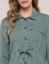 Sobrecamisa beige de lino liviano, con cuello camisero, cierre frontal de botones carey y bolsillos en el pecho. Cuenta con cordón ajustable en la cintura y mangas largas.